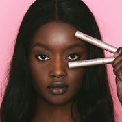 Model holding Lash Therapy Australia lash and brow growth serums on pink background